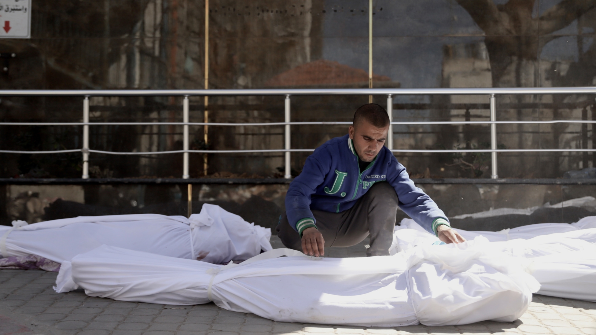 Man in al-Shifa Hospital looking over the shrouds enveloping the bodies following the attack (Mohammed al-Hajjar/MEE).