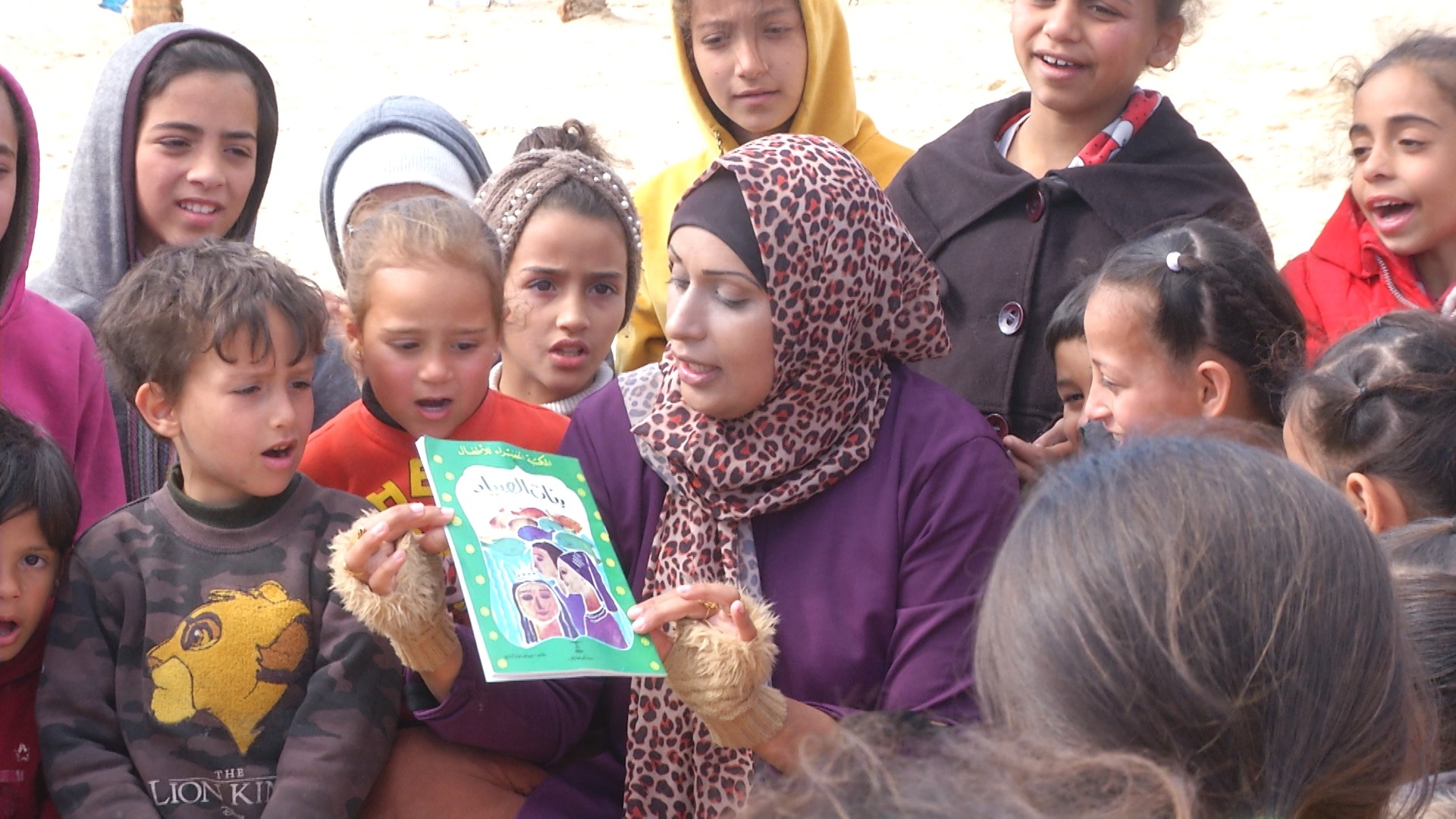 Children surround Asma as she tells them stories to help them cope with the mental distress caused by the war, February 2024 (MEE/Hala Alsafadi)