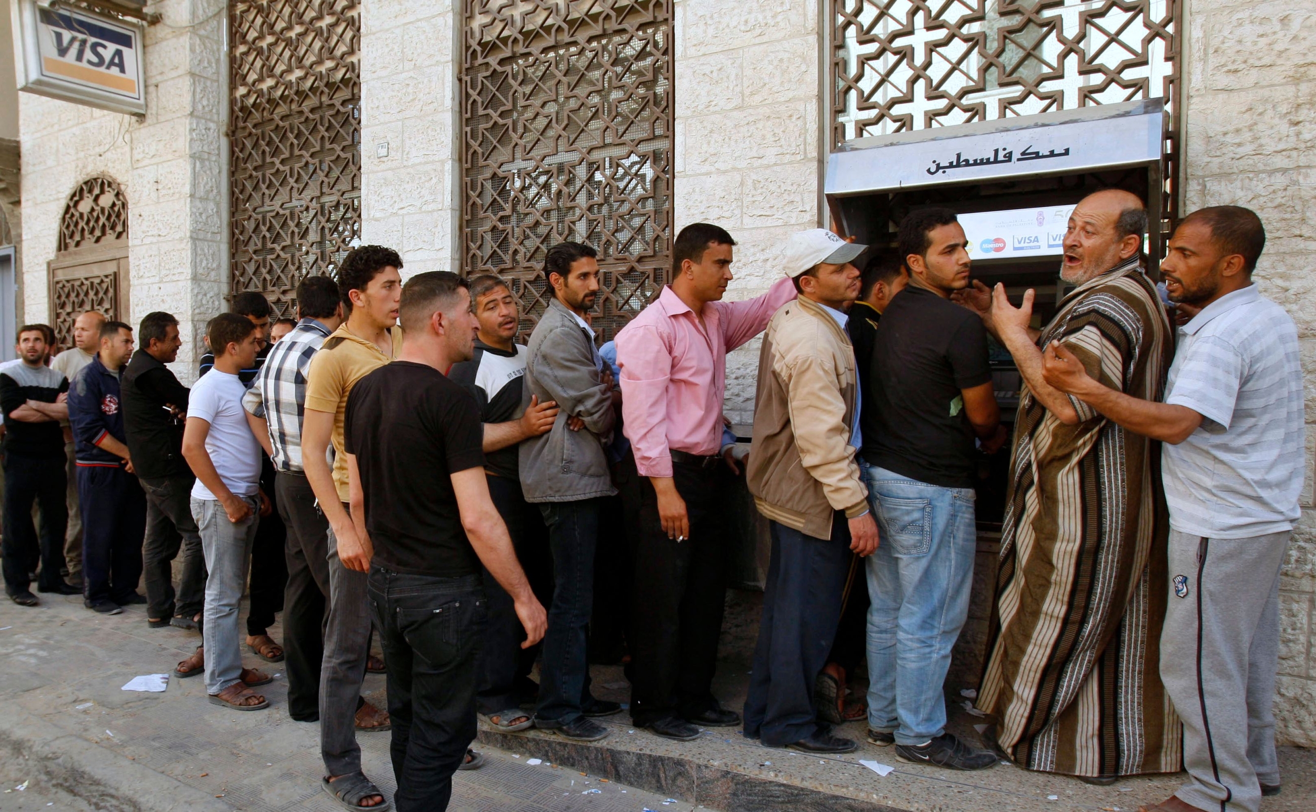 Palestinian Authority (PA) employees queue to receive their salaries from an ATM in Khan Younis in the southern Gaza Strip in April 2012 (Reuters)