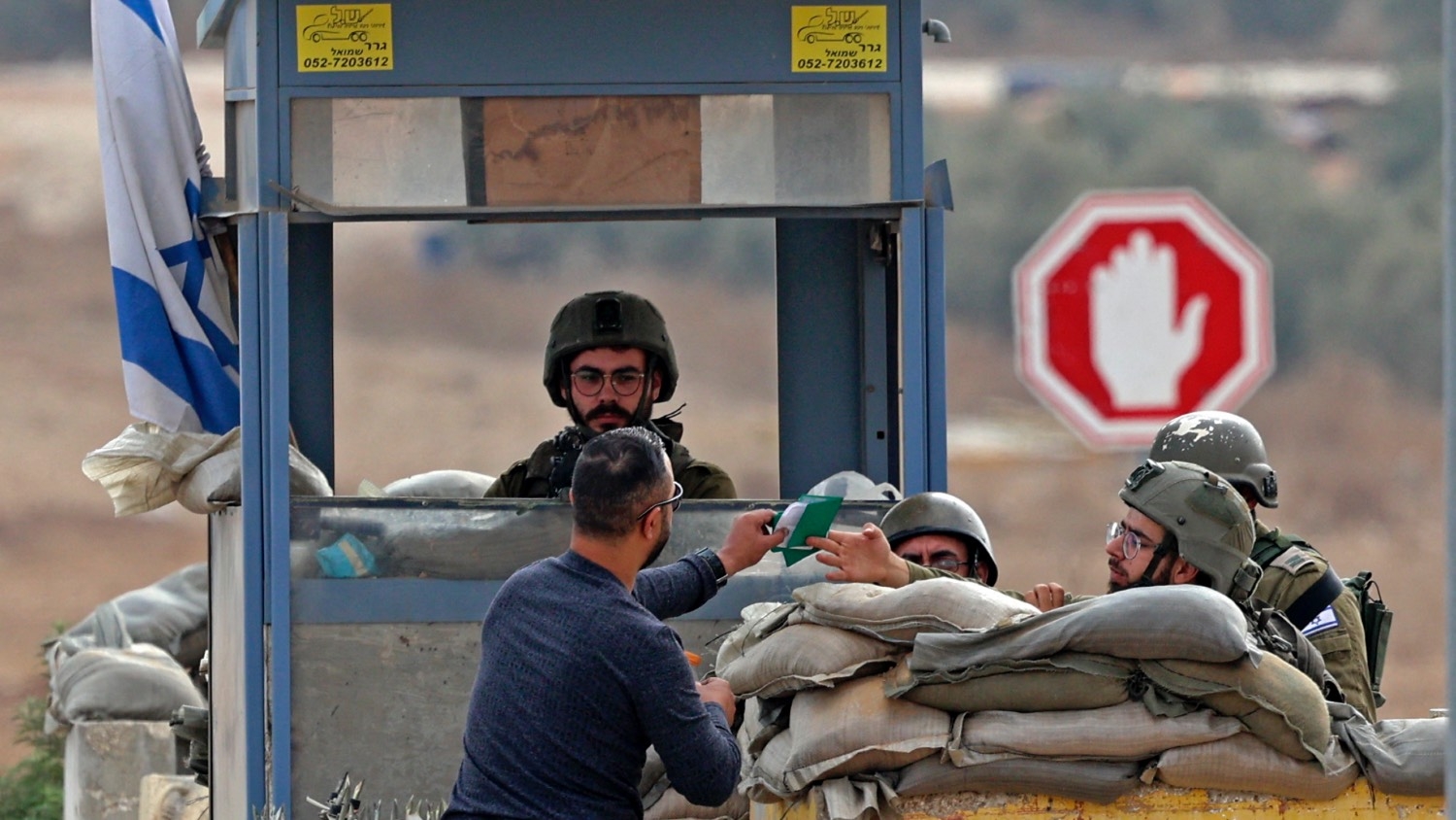 A Palestinian hands his documents to an Israeli soldier manning a checkpoint in the occupied West Bank on 26 October 2022.