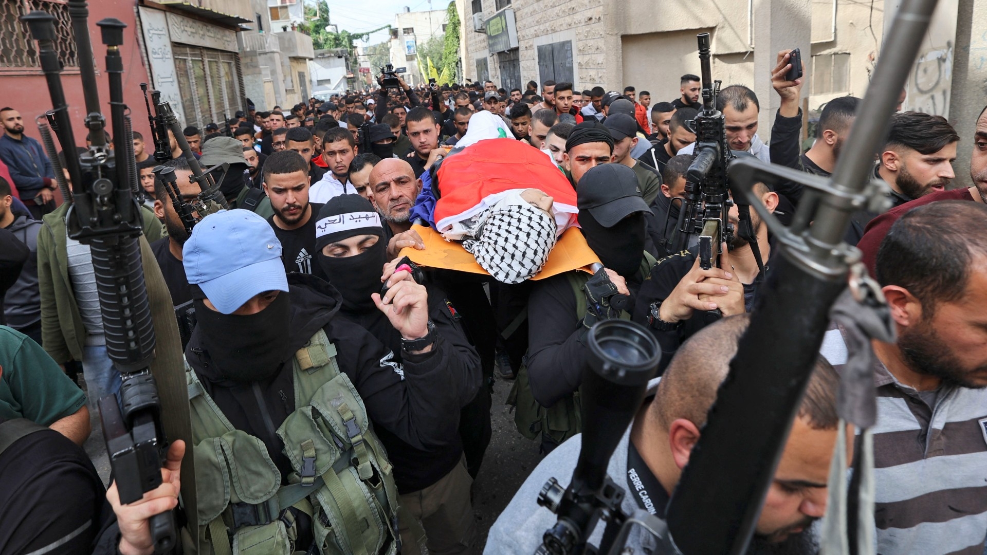 Palestinian mourners carry the body of Mahmoud al-Saadi, a youth who was reportedly killed during a raid by Israeli forces on 21 November 2022 in the occupied West Bank city of Jenin (AFP)
