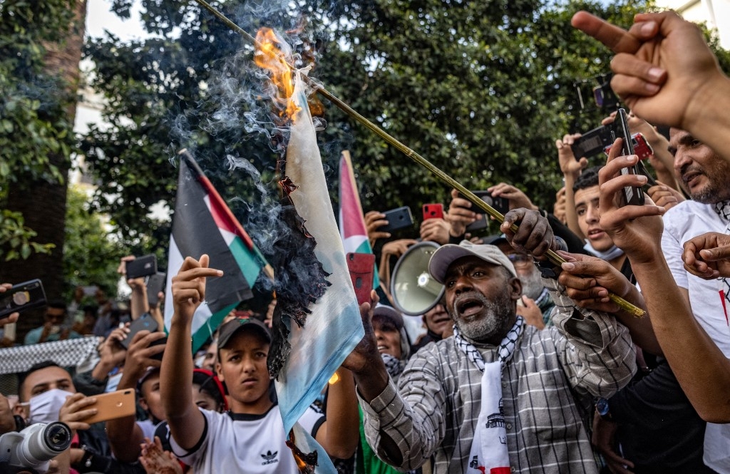 Des Marocains brûlent le drapeau israélien lors d’une manifestation contre la normalisation à Rabat, le 16 mai 2021 (AFP/Fadel Senna)