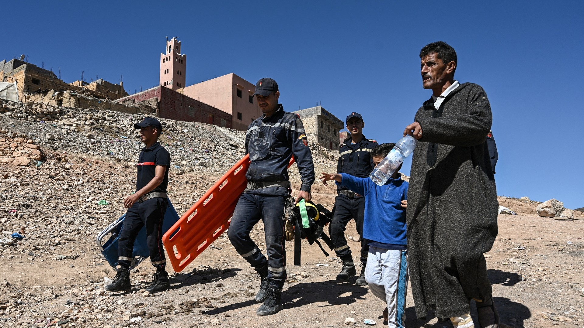 A resident (right) leads civil defence responders to an injured survivor of the deadly 8 September earthquake in the High Atlas mountains of central Morocco on 11 September