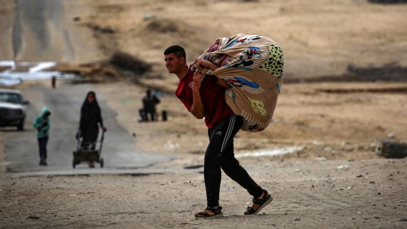 Palestinians carry their belongings as they prepare to flee Rafah, Gaza, on 13 May 2024 (AFP)