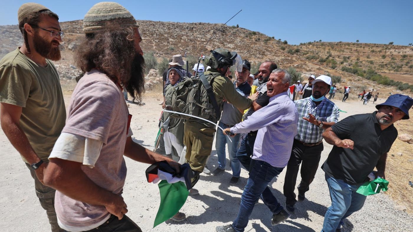 Israeli settlers scuffle with Palestinian protesters during a demonstration against settlement expansion, in the village of al-Mughayer in the occupied West Bank, on 29 July, 2022 (AFP)