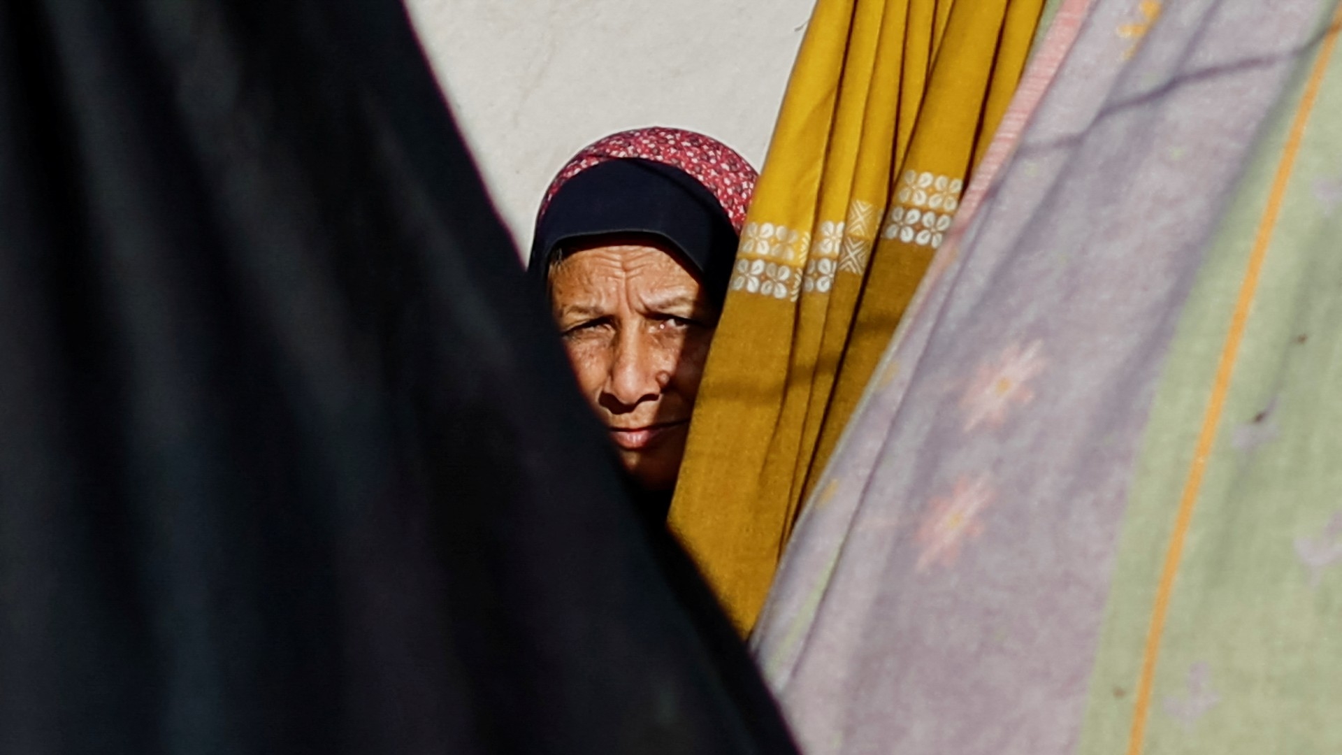 A displaced Palestinian woman, who fled her house due to Israeli strikes, looks on inside a tent camp in Rafah in the southern Gaza Strip, 22 January 2024 (Reuters/Ibraheem Abu Mustafa)