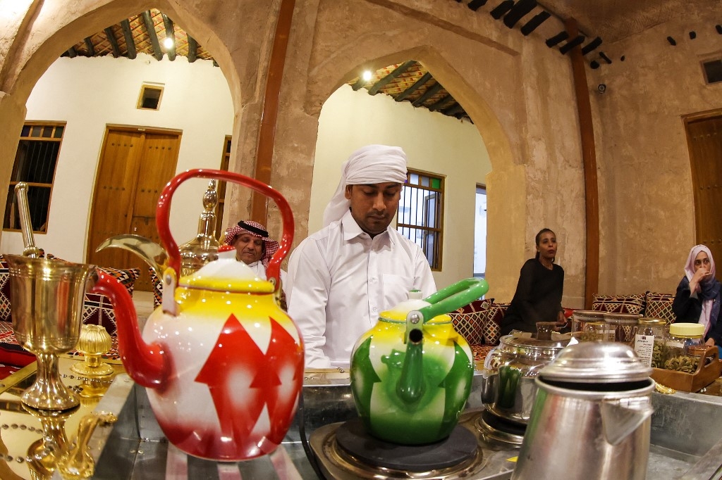 Un homme sert du gahwa traditionnel, préparé en torréfiant des grains de café puis en les faisant bouillir avec de la cardamome et du safran, à la maison culturelle Embrace Doha dans le souk Al-Wakrah, au sud de la capitale Doha, le 13 septembre 2022 (AFP/Karim Jaafar)