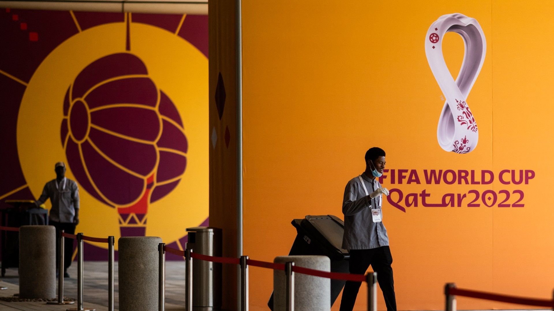 Workers move trash bins past Qatar 2022 FIFA World Cup football tournament posters in Doha on 21 October 2022 (AFP)