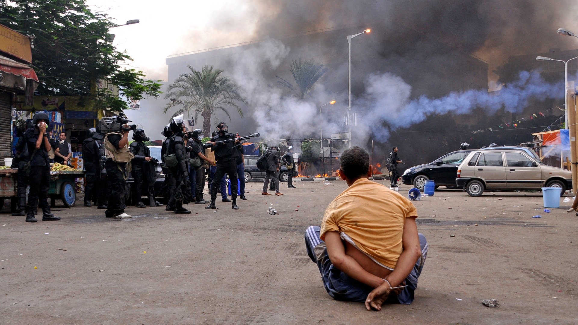A handcuffed protester sits on the ground as Egyptian security forces move in to disperse supporters during the Rabaa massacre in Cairo, Egypt on 14 August 2013 (AFP)