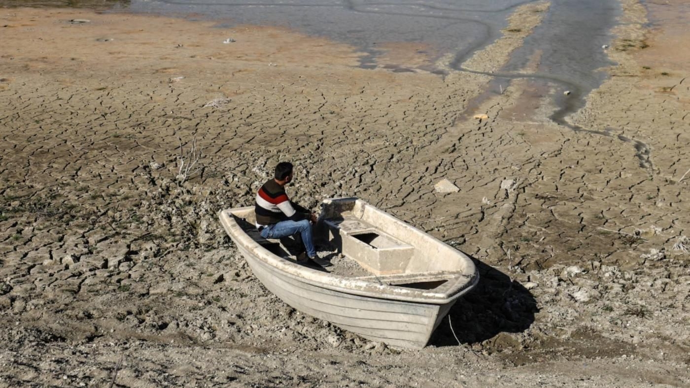 Un homme est assis dans une barque à l’endroit où se trouvait autrefois le lac d’al-Duwaisat. Situé dans l’ouest de la province d’Idleb, le lac s’est asséché en raison des effets du changement climatique et des dégâts subis par les infrastructures (MEE/Izzeddin Kasim)