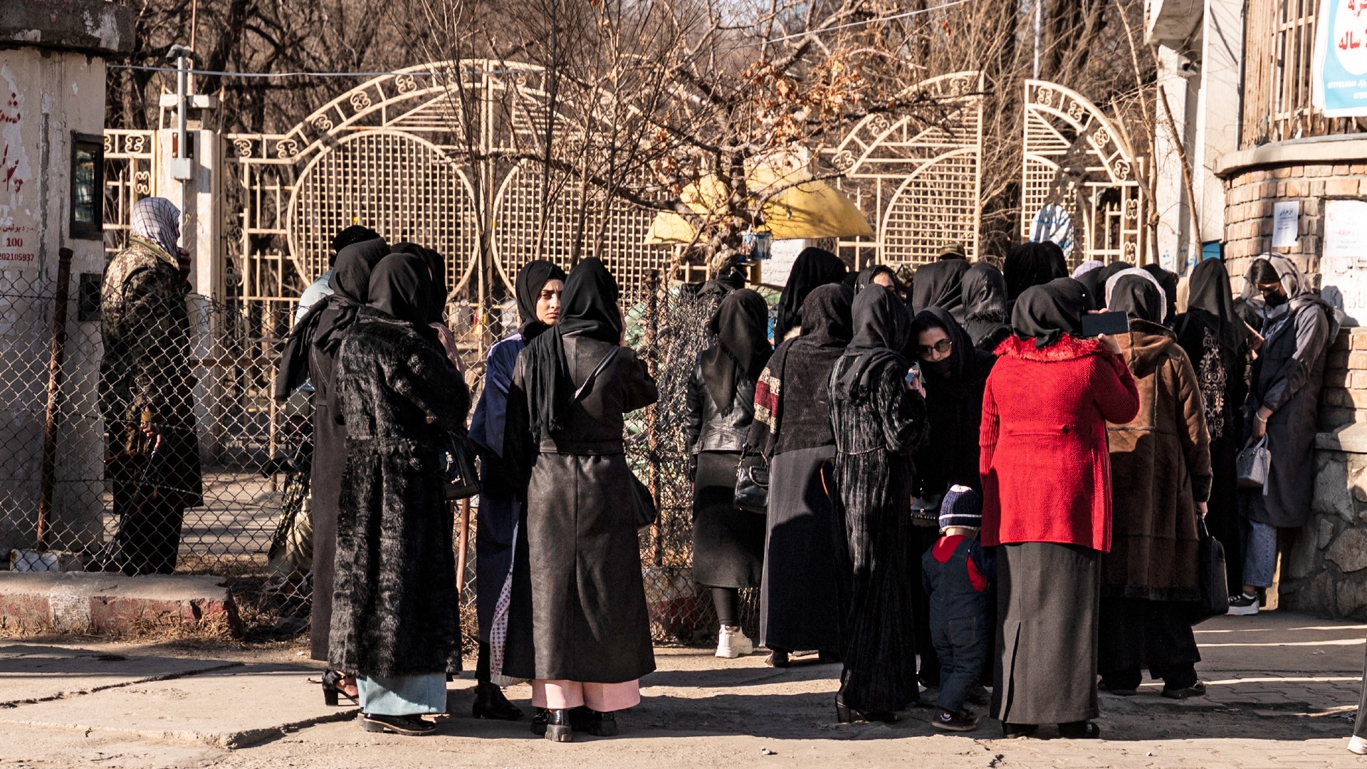 Afghan female university students are stopped by Taliban security personnel next to a university in Kabul on 21 December 2022 (AFP)