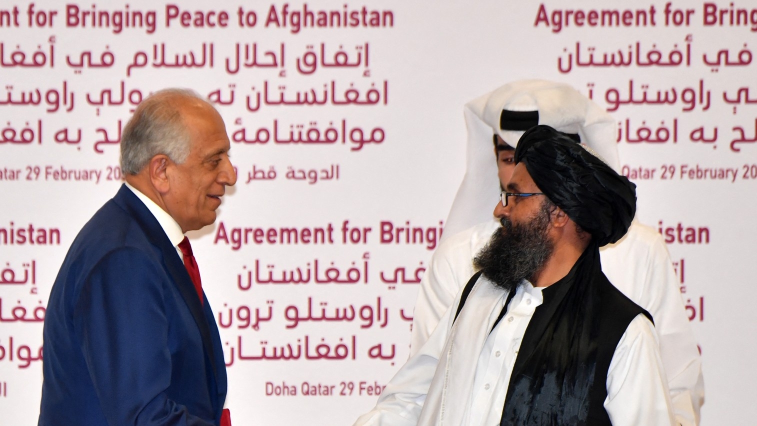 US envoy to Afghanistan Zalmay Khalilzad and Taliban co-founder Mullah Abdul Ghani Baradar shake hands after signing a peace agreement in Doha on 29 February 2020.