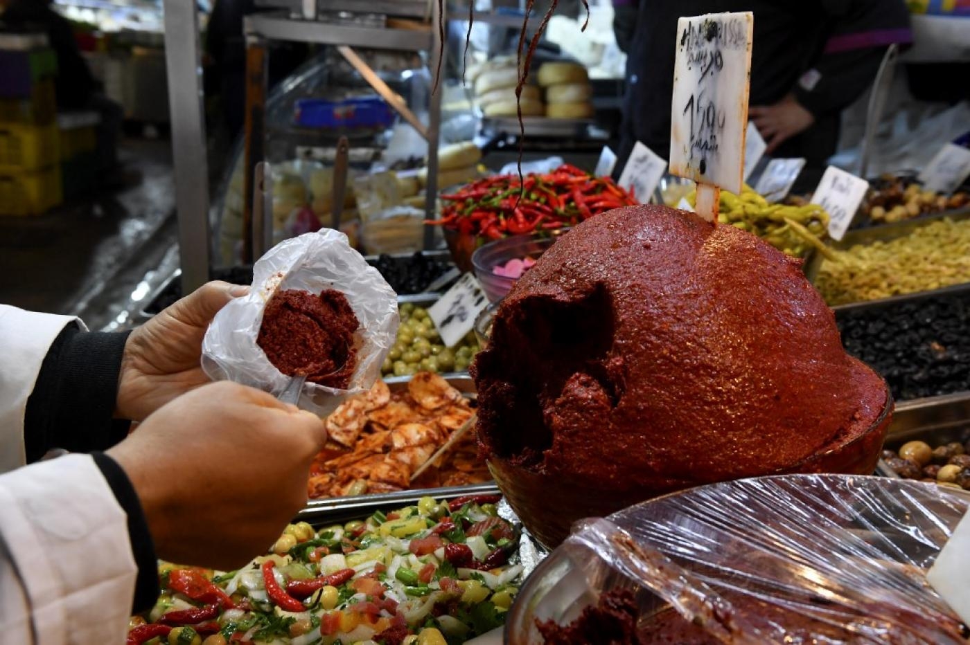 Un commerçant sert de la harissa à un client dans le marché central de la capitale Tunis le 1er décembre 2022 (AFP/Fethi Belaïd)