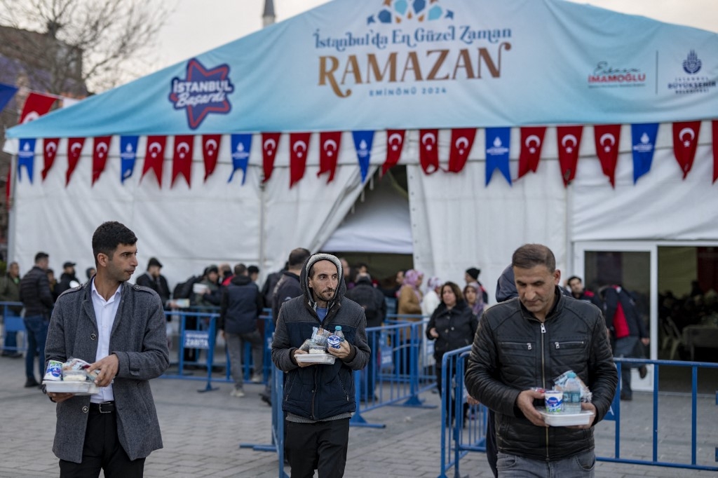 Les fidèles reçoivent des repas pour l’iftar des autorités locales pendant le mois sacré du Ramadan à Istanbul le 15 mars 2024 (AFP/Yasin Akgul)