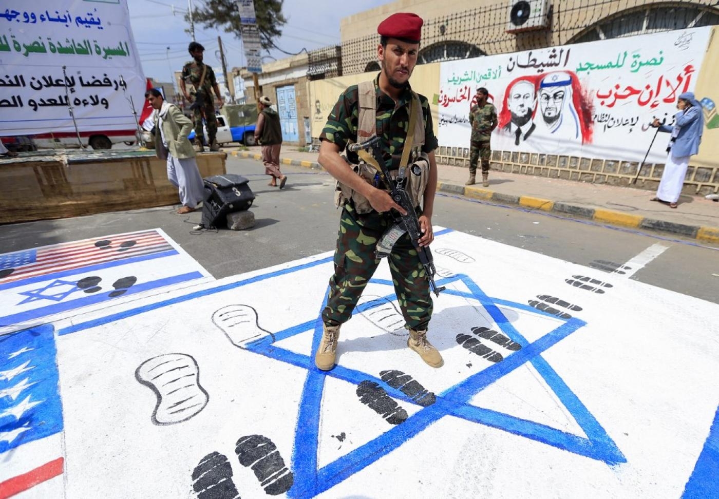 Un combattant yéménite piétine les drapeaux israélien et américain pendant un rassemblement à Sanaa, le 22 août, pour protester contre l’accord négocié par les Américains afin de normaliser les relations entre Israéliens et Émiratis (AFP)
