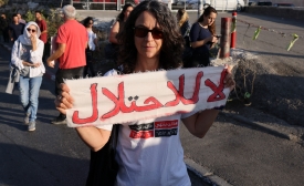 Une femme tient une banderole où est écrit « Non à l’occupation » lors d’un rassemblement organisé par des militants étrangers, palestiniens et israéliens dans le quartier de Sheikh Jarrah à Jérusalem-Est occupée, le 14 octobre 2022 (AFP)