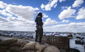 Un membre des forces kurdes de sécurité responsables du camp monte la garde alors qu’un groupe de familles syriennes est libéré du camp d’al-Hol, le 18 mars 2021 (Delil Souleiman/AFP)