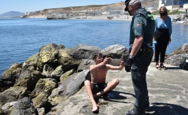 Un membre de la Guardia Civil (police à statut militaire) aide un migrant mineur à son arrivée par la nage à Ceuta, le 19 mai 2021 (AFP/Antonio Sempere)