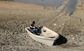 Un homme est assis dans une barque à l’endroit où se trouvait autrefois le lac d’al-Duwaisat. Situé dans l’ouest de la province d’Idleb, le lac s’est asséché en raison des effets du changement climatique et des dégâts subis par les infrastructures (MEE/Izzeddin Kasim)