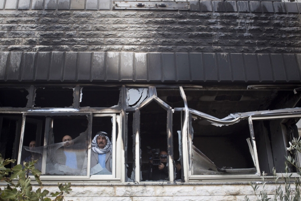 A Palestinian man inspects the damage inside a home that was attacked with petrol bombs northeast of Ramallah on 23 November, 2014 (MEE/Oren Ziv)