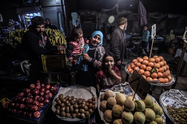 Egyptians smile for a photo as they buy fruit from a street vendor at a market in the Menufiya province, north of Cairo, on 22 February 2018 (AFP)