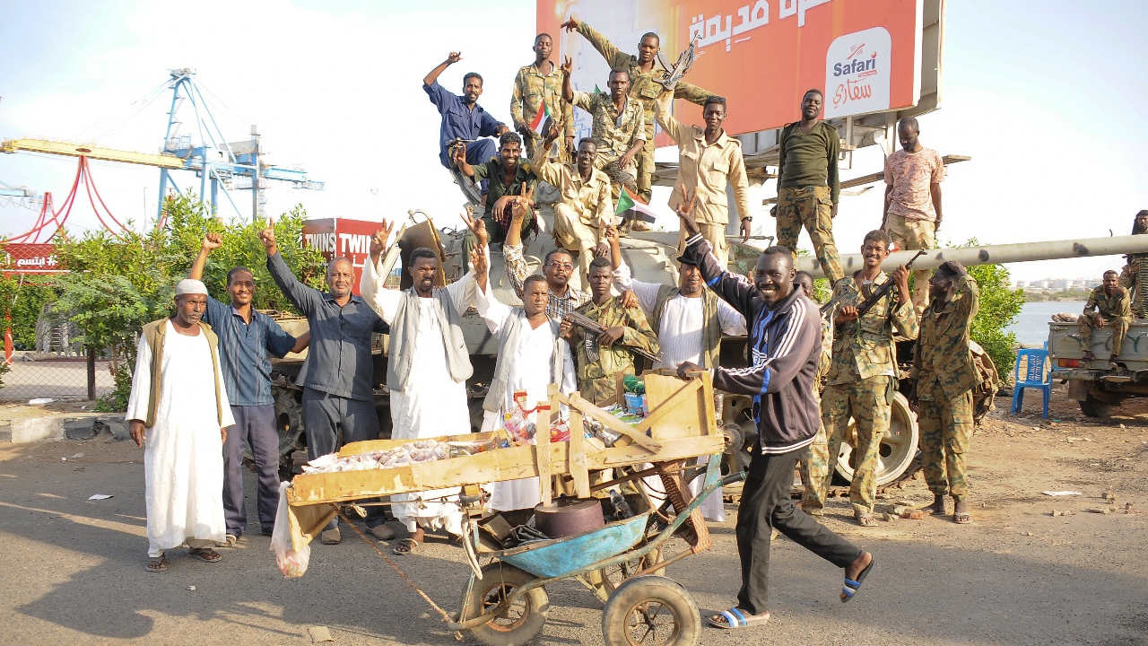 Des citoyens manifestent leur joie aux côtés de soldats de l’armée soudanaise fidèles au chef de l’armée Abdel Fattah al-Burhan qui occupent une position à Port-Soudan, ville bordant la mer Rouge, le 29 avril 2023 (AFP)