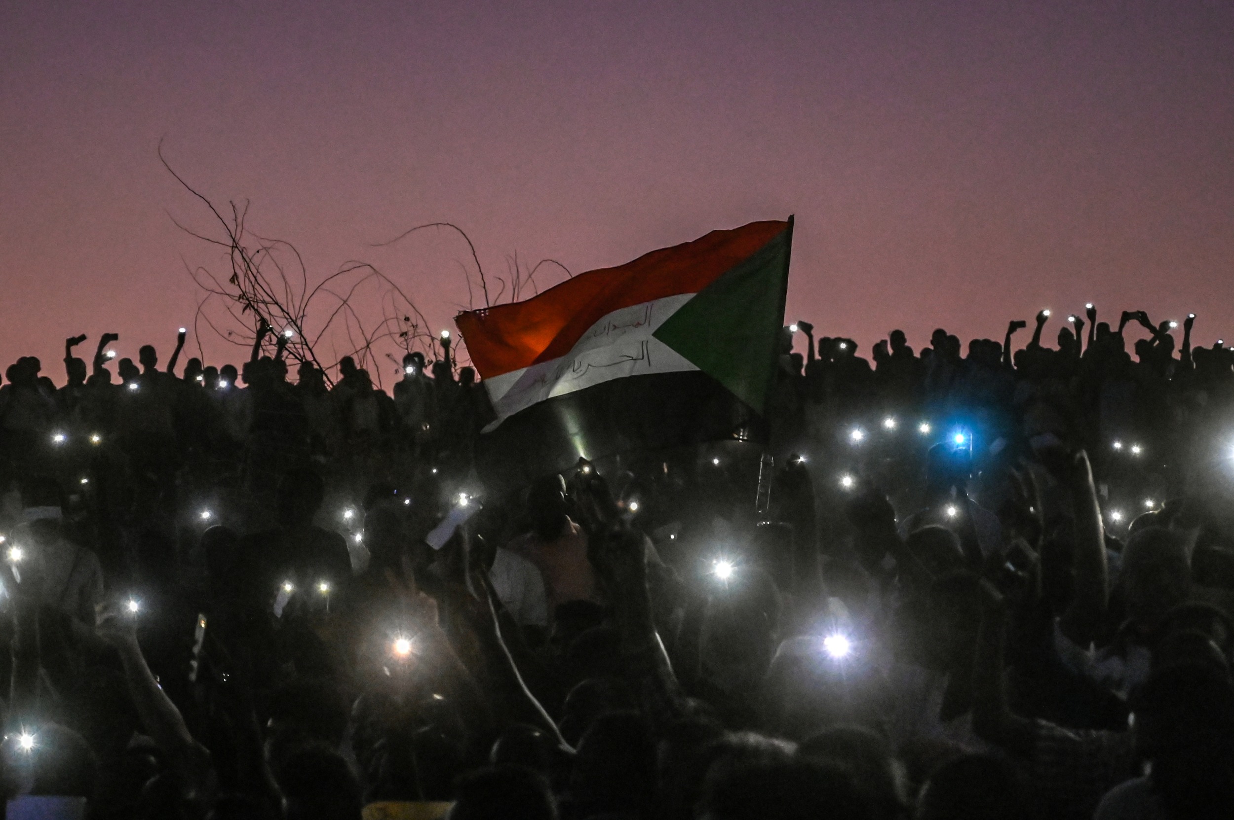 Sudanese protesters open their smartphones lights during a protest outside the army headquarters in the capital Khartoum on 21 April 2019 (AFP)
