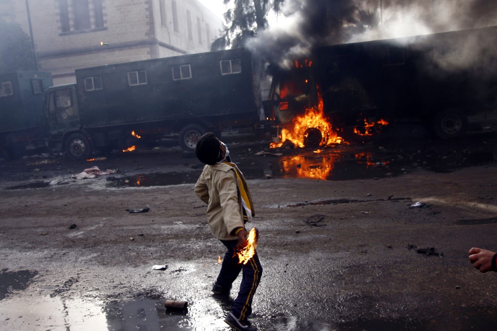 A demonstrator throws a fuel bomb at anti-riot police vehicles in Suez on 28 January 2011 (AFP)