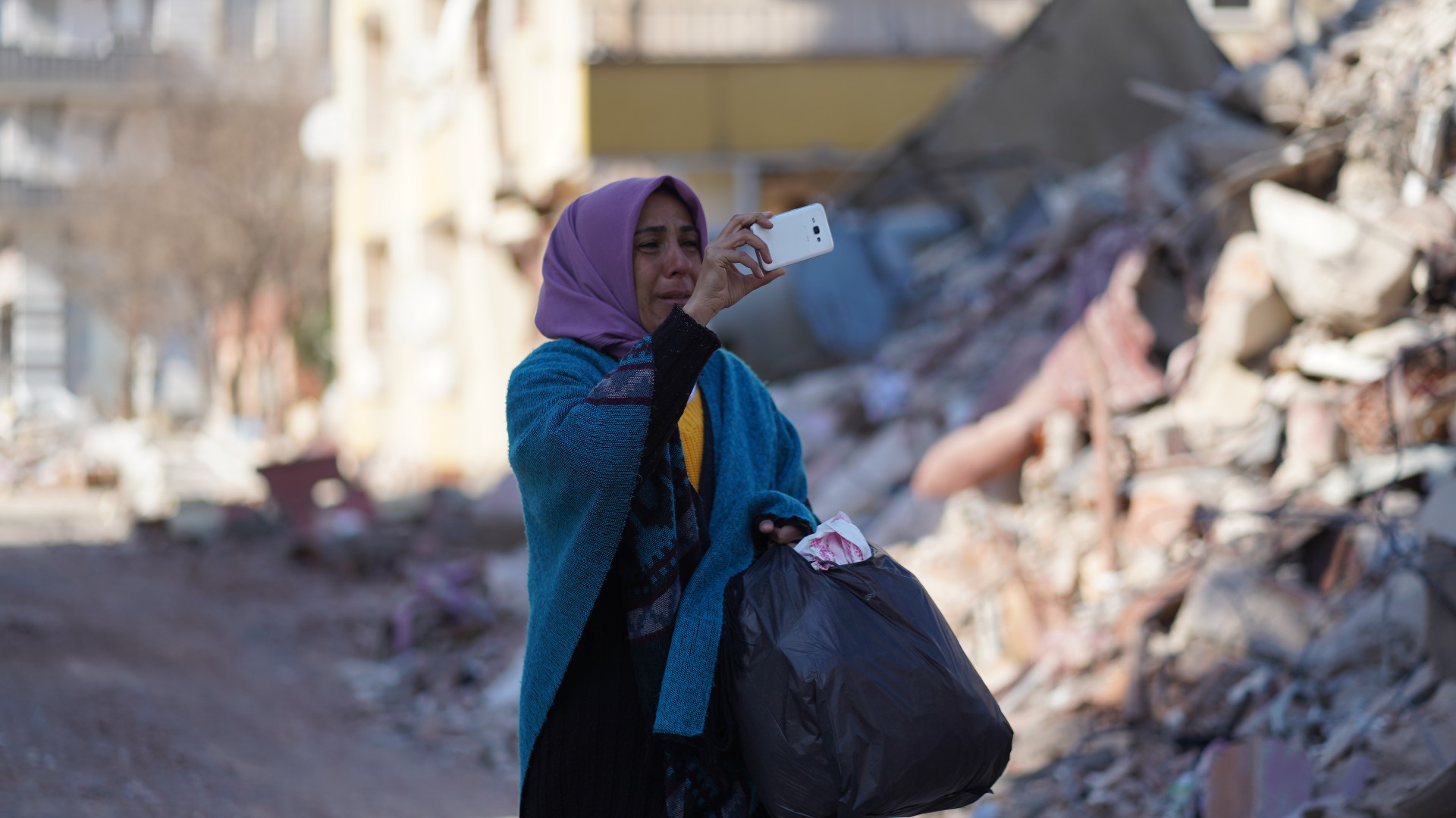 A woman records the devastation on her phone in Nurdagi, a town in Gaziantep Province on 13 February 2023 (MEE/Mohamed Mossomo)