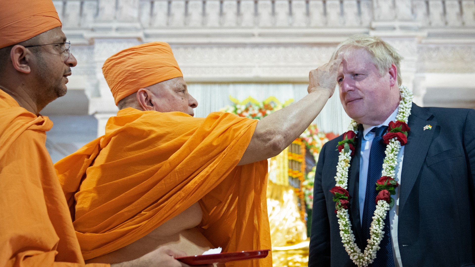  Hindu holyman puts a traditional 'tilak' on the forehead of Britain's Prime Minister Boris Johnson (2R) during his visit at the Swaminarayan Akshardham temple in Gandhinagar