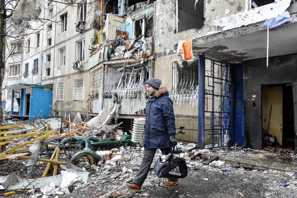 A man leaves an apartment building damaged after shelling in Kharkiv, Ukraine, on 8 March 2022 (AFP)