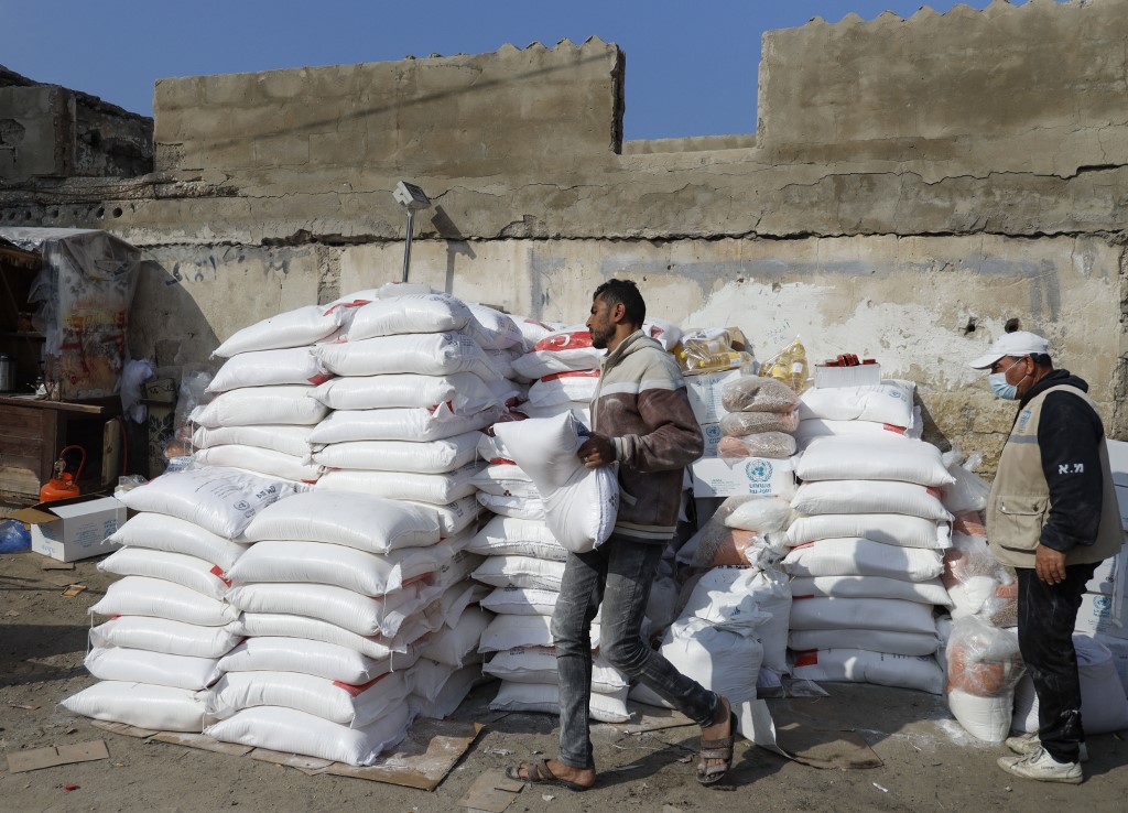 Employees stack food rations outside a UNRWA aid centre in Gaza on 12 December (AFP)