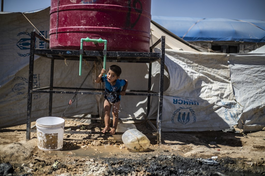 Un jeune Syrien déplacé en train de boire dans un réservoir à al-Hol en juillet (AFP)