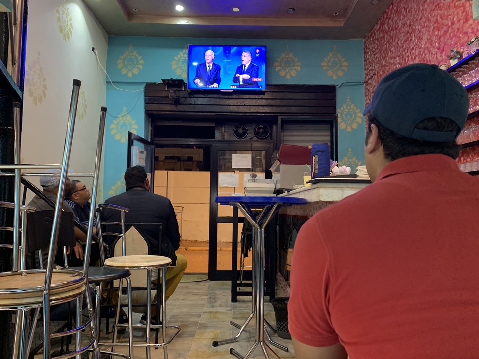 Tunisians in Tunis look on as the country's presidential candidates challenge each other in the TV debate (MEE/Faisal Edroos)