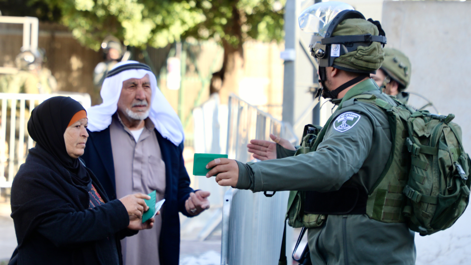 A couple shows their permits to Israeli guards in Bethlehem (Mosab Shawer/MEE)