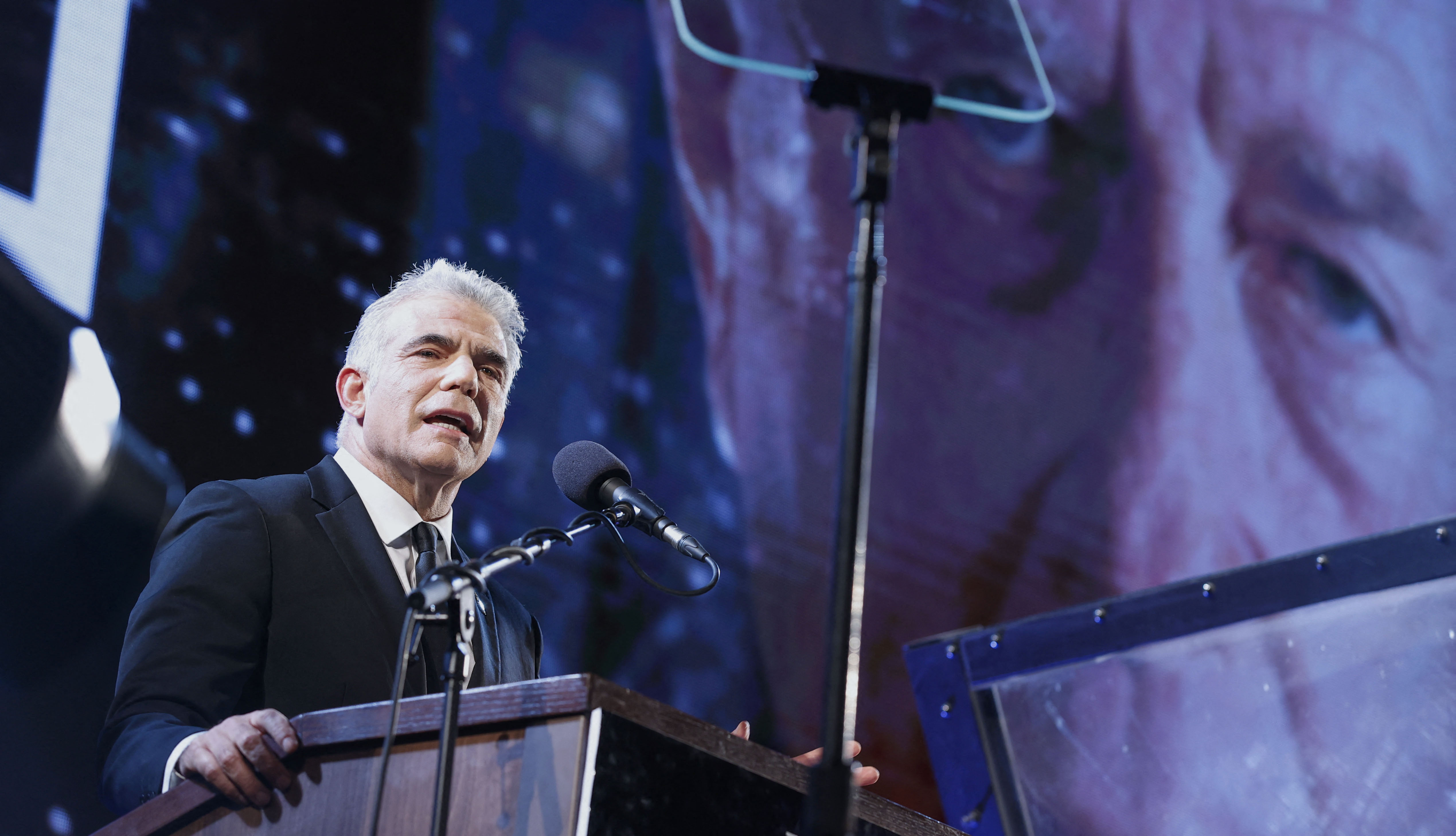 Israeli opposition leader Yair Lapid delivers a speech during a rally to mark the 25th anniversary of the assassination of former Prime Minister Yitzhak Rabin (portrait), at Rabin Square in the coastal city of Tel Aviv on November 7, 2020.