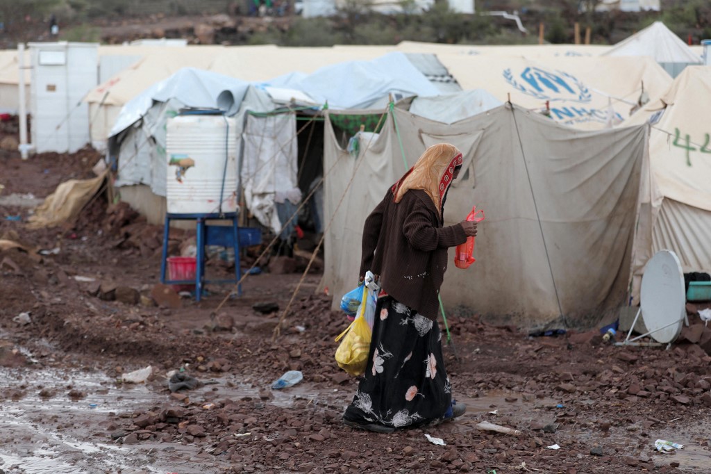 A woman walks past tents at a temporary camp for people displaced by the conflict, which has been inundated after heavy rains, in Yemen's southwestern province of Taiz, on October 9, 2021.