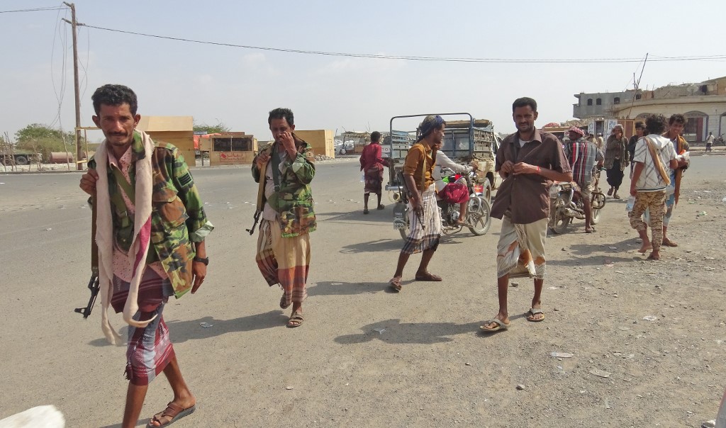 Yemeni fighters loyal to the Saudi-backed president walk down a street in Hodeidah on 18 December (AFP)